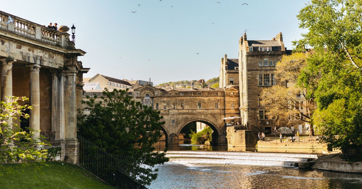 Pulteney Bridge and weir on the River Avon in Bath, with Georgian stone buildings behind.