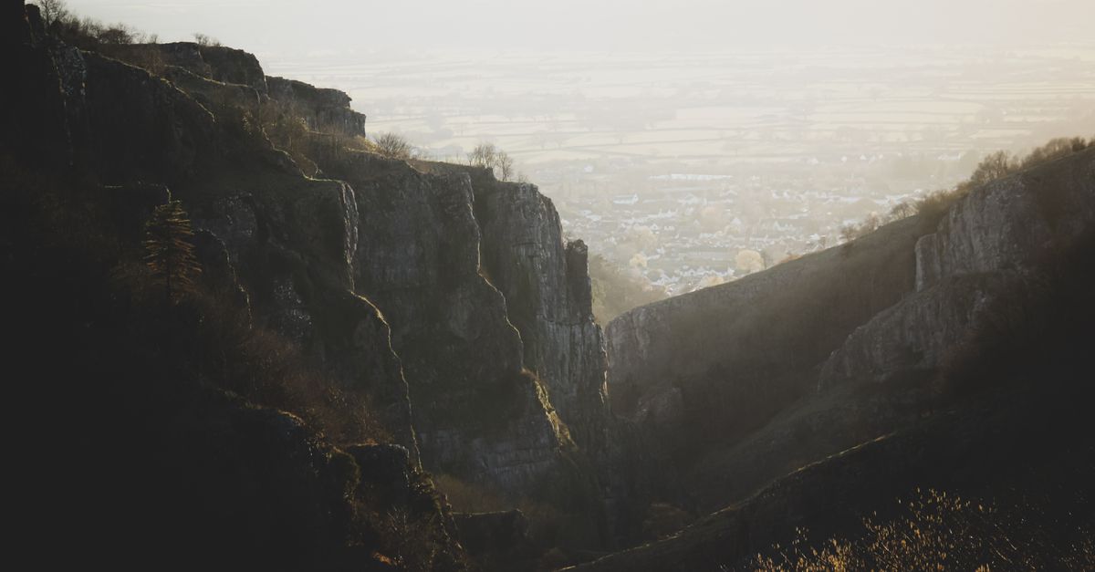 Cheddar Gorge's limestone cliffs at dawn, with the village visible in the valley below.